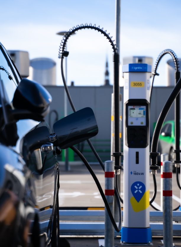 Ignitis ON laadimisjaam laeb autot väljas, rõhutades laadimiskaabli detaile.