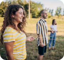 Naine naeratab ja räägib õues mehega, tagaplaanil on näha teine inimene.