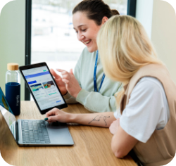 Kaks naist istuvad laua taga ja vaatavad sülearvutit, arutades detaile.