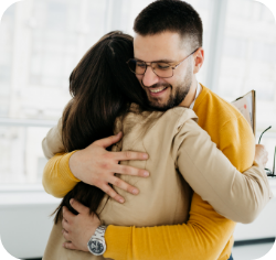 Mees kallistab naeratades naist, mõlemad kannavad sooje riideid.