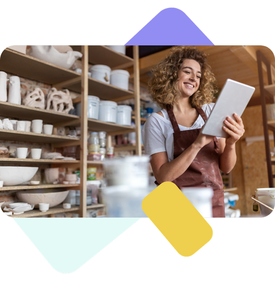 Naine töökojas naeratab, kasutades tahvelarvutit.